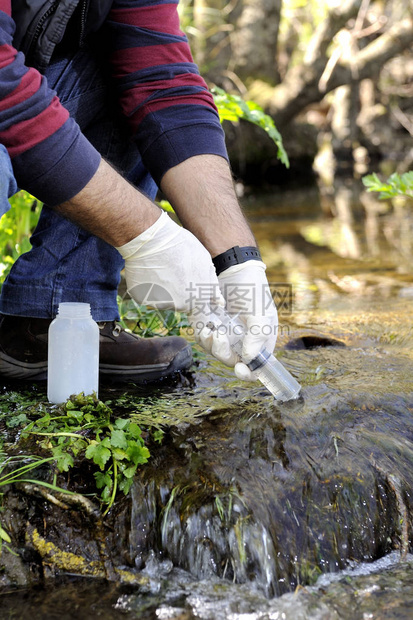 在水道中收集样本以分析其污染和研究其特征的生物学家图片