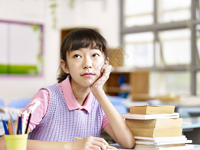 坐在书桌的亚洲小学生女孩在课堂上思图片