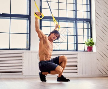 运动男子在大明窗背景上用健身式的Tr图片
