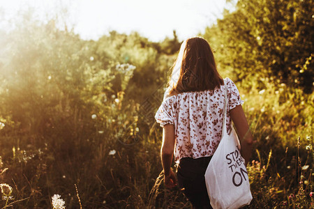 时髦的时髦女孩带着生态袋在阳光照射图片