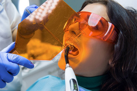 看牙医的女病人凹面镜和光固化机图片