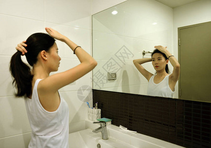 亚洲女人在浴室的镜子前梳头图片