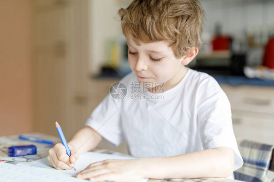 可爱的快乐学校孩子男孩在家做作业的画像小孩用彩色铅笔在室内写字小学和教育孩子学习图片