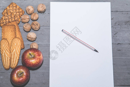 桌子上的饼干核桃苹果和白纸顶视图图片