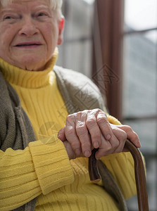 老妇人双手拄着拐杖坐着背景图片