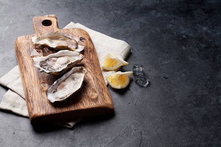 木板上露开的牡蛎冰和柠檬在石板上图片