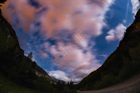 星空与运动模糊彩云和明亮的月光欧洲阿尔卑斯山广阔的夜景图片