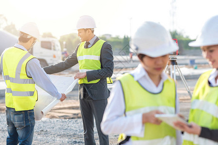 工程师和建筑商在早晨在建筑工地的团队期间在阳背景图片