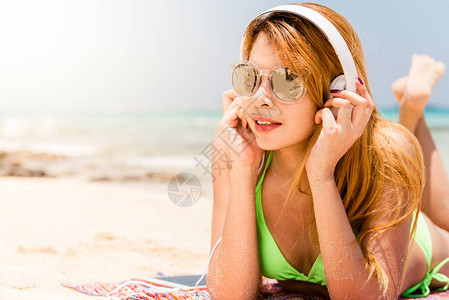 快乐的海滩女人在智能手机上放耳机听音乐暑假期间穿着比基尼的休闲女孩在手机上通过无线4g享受有趣图片