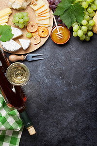 白葡萄酒葡萄面包蜂蜜和芝士在石桌上图片