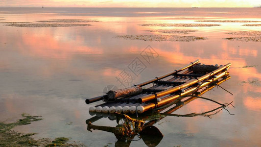 竹筏漂浮在热带日落的倒影中图片