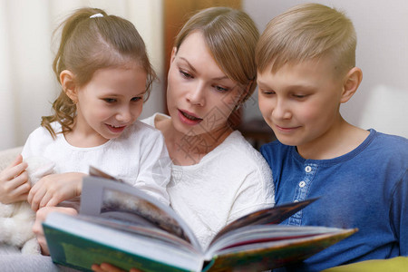 美丽的母亲正在给她年幼的孩子们读书图片