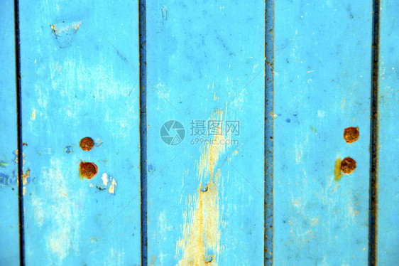 蓝色木门上的油漆剥落和生锈的钉子图片