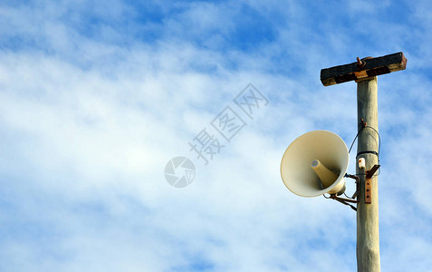 在蓝色天空背景的电线杆上安装户外扩音器警报系统复图片