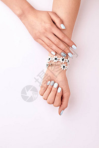 白色背景的鲜花手镯白蓝色女指甲和莱茵图片