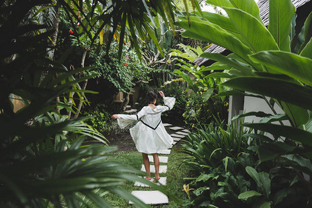 女人穿着白色连衣裙在热带花园里散步图片
