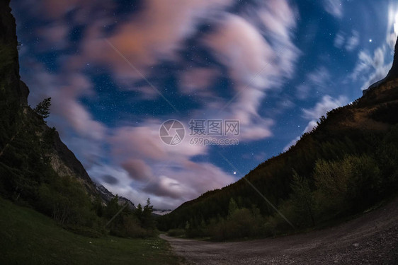 与运动模糊彩云和明亮的月光欧洲阿尔卑斯山广阔的夜景图片