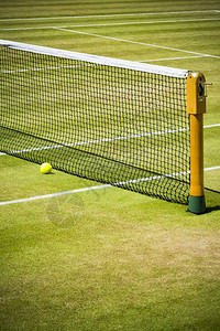 阳光下专业网球场的球赛在靠近网图片