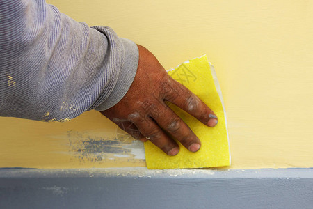 工匠用砂纸处理房屋的墙壁图片