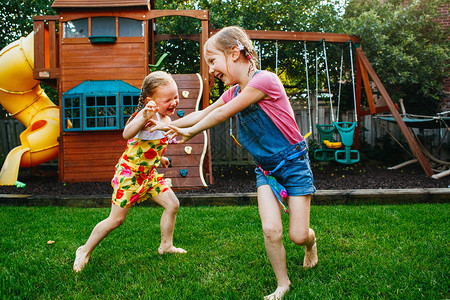 两个小女孩姐妹在家后院打架的画像朋友女孩玩得开心兄弟姐妹争吵在一起玩耍的生活方式坦图片