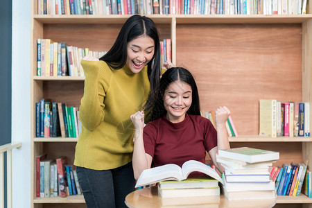 两名亚洲女学生在大学图书馆阅读书籍图片