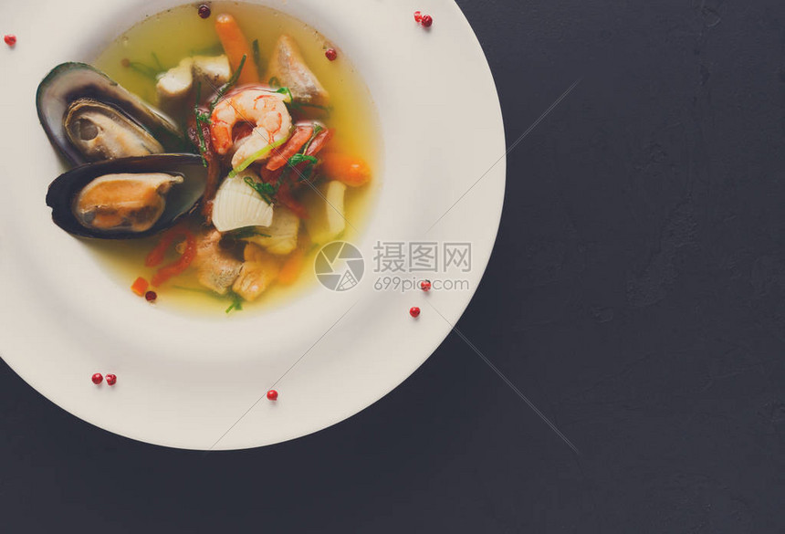 法国美食餐厅海鲜汤配白鱼虾和贻贝在盘子里撒上香料黑色背景新鲜烹制的独家餐点图片