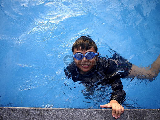 一个小男孩在游泳池里游泳的照片图片