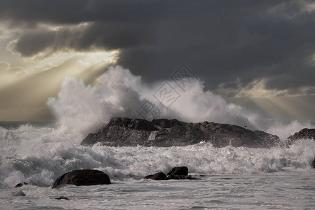 大海浪在日落时冲过岩背景图片