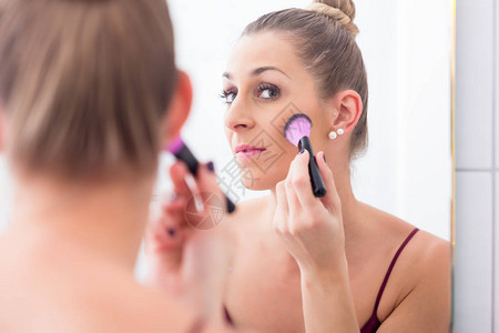 女人在浴室镜子前用化妆刷子图片
