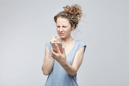 特写肖像焦虑或震惊的年轻自由职业者女人看着电话看到坏消息或照片图片