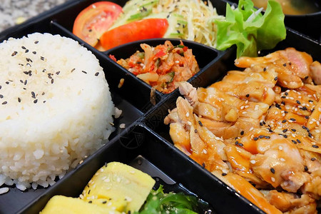 黑椒鸡肉饭传统日本料理便当盒或多层盒配照烧鸡肉饭沙拉玉子烧或煎蛋卷日式裙带菜或海背景