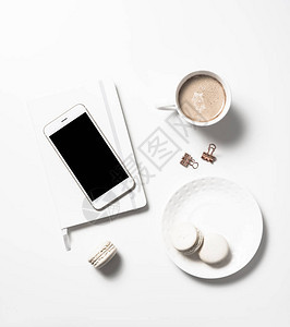 白色女公寓用白桌背景的蜜蜂马卡龙咖啡和智能手机模型铺图片