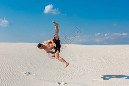 年轻的Parkour男人的肖像在沙子上做翻转或摩擦开始反弹的一图片