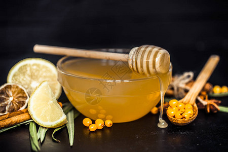 黑色背景上用蜂蜜和一勺蜂蜜特写和柠檬组成的透明盘子有机食品图片