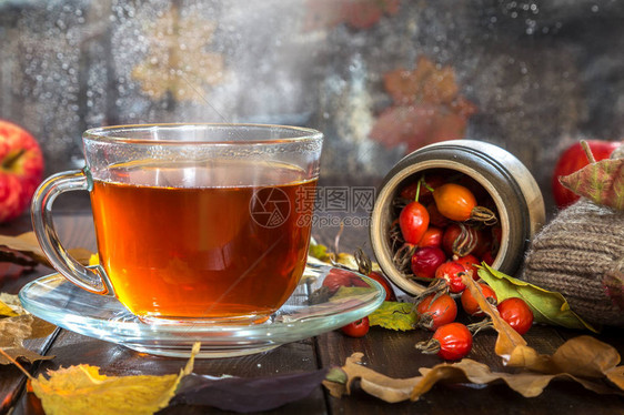 在木背景的秋叶和浆果中喝杯热茶图片