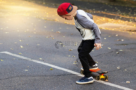 带着便士滑板的城市小男孩年轻的孩子在公园里骑着滑板城市风格城市孩子孩子图片