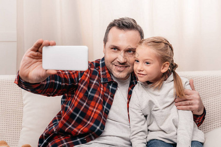 快乐的父亲和女儿用智能手机一图片