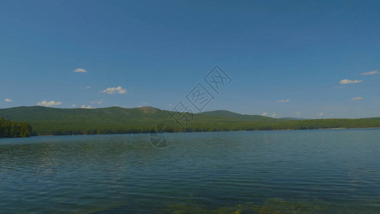 湖边美丽的蓝色清澈水海岸的森林风景背景图片