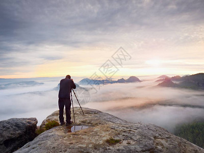 摄影师用取景器取景摄影爱好者在岩石山顶享受秋季大自然的作品梦幻般的风景背景图片