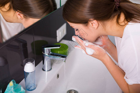女性洗脸泼水女人早上用泡沫清洁剂洗脸背景