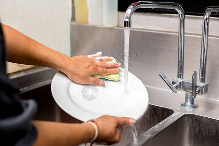 妇女用自来水洗手厨房水槽图片