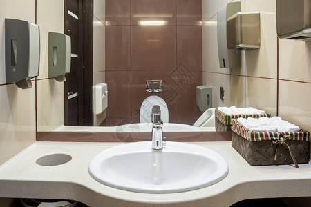在公共厕所里用纸毛巾自动干洗手机干下水盆棕墙壁和瓷砖图片