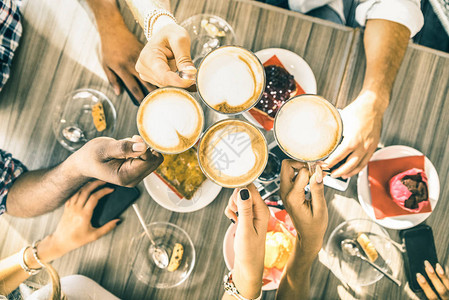 朋友们在咖啡吧餐厅喝卡布奇诺人们在时尚自助餐厅举手敬酒与男和女在咖啡馆的冬季饮品概念温暖背景图片