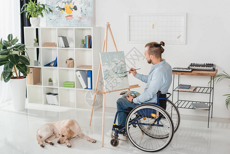 坐在轮椅上在帆布上绘画的残疾男子图片