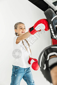 父亲在打拳击手套时训练可爱的小女儿图片