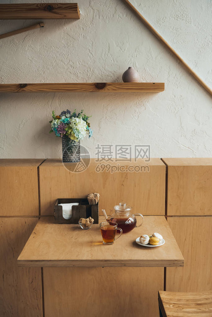 在咖啡厅的桌子上放着一杯茶和杏仁饼的玻璃茶壶图片