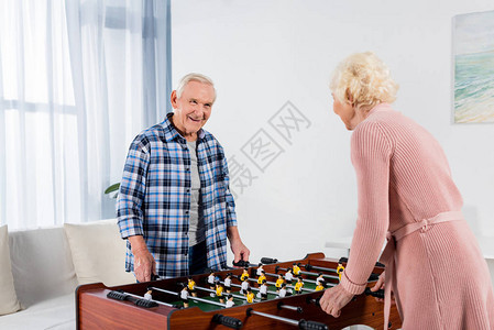 快乐的老年夫妇踢桌上足球图片