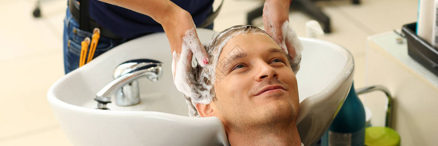 女手在理发前用洗发水在理发店给英俊的微笑男人洗头角蛋白修复最新