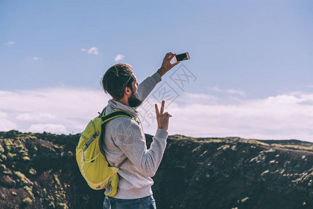 在冰岛美丽的火山湖附近带着背带自拍和智能图片