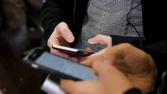 两个年轻人手中的智能手机特写镜头新一代在咖啡馆关闭沟通理念夫妇使用数字小工具进行网上购物聊天图片